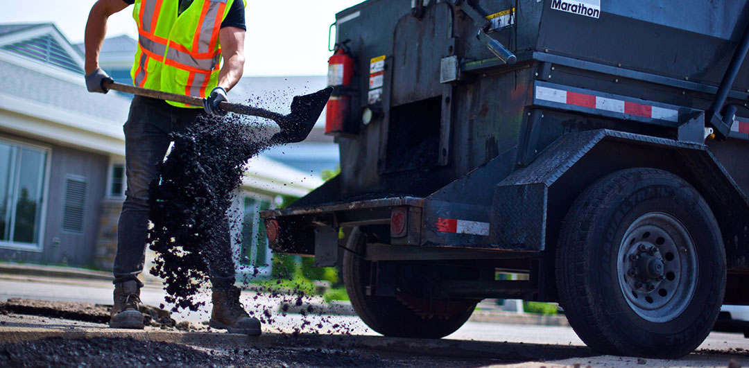 Canadian Property Stars Employee shoveling hot asphalt from the HMT4000ODL into the pothole