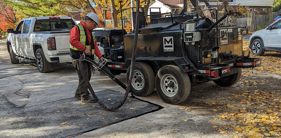 6ixview worker using the KERA180BRE to pour hot rubber in the channel that connects old with new asphalt.