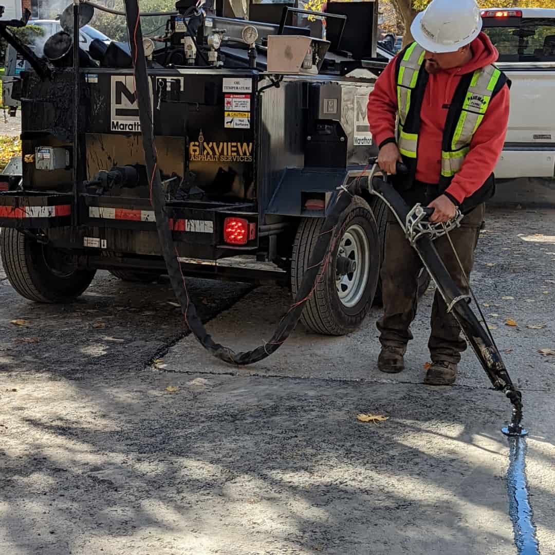 6ixview worker using the kera370bre to crack seal a driveway in a suburb area