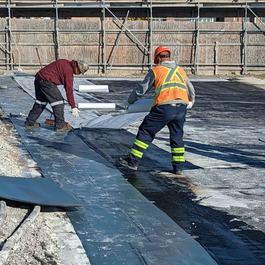  two workers applying the two ply waterproofing membrane