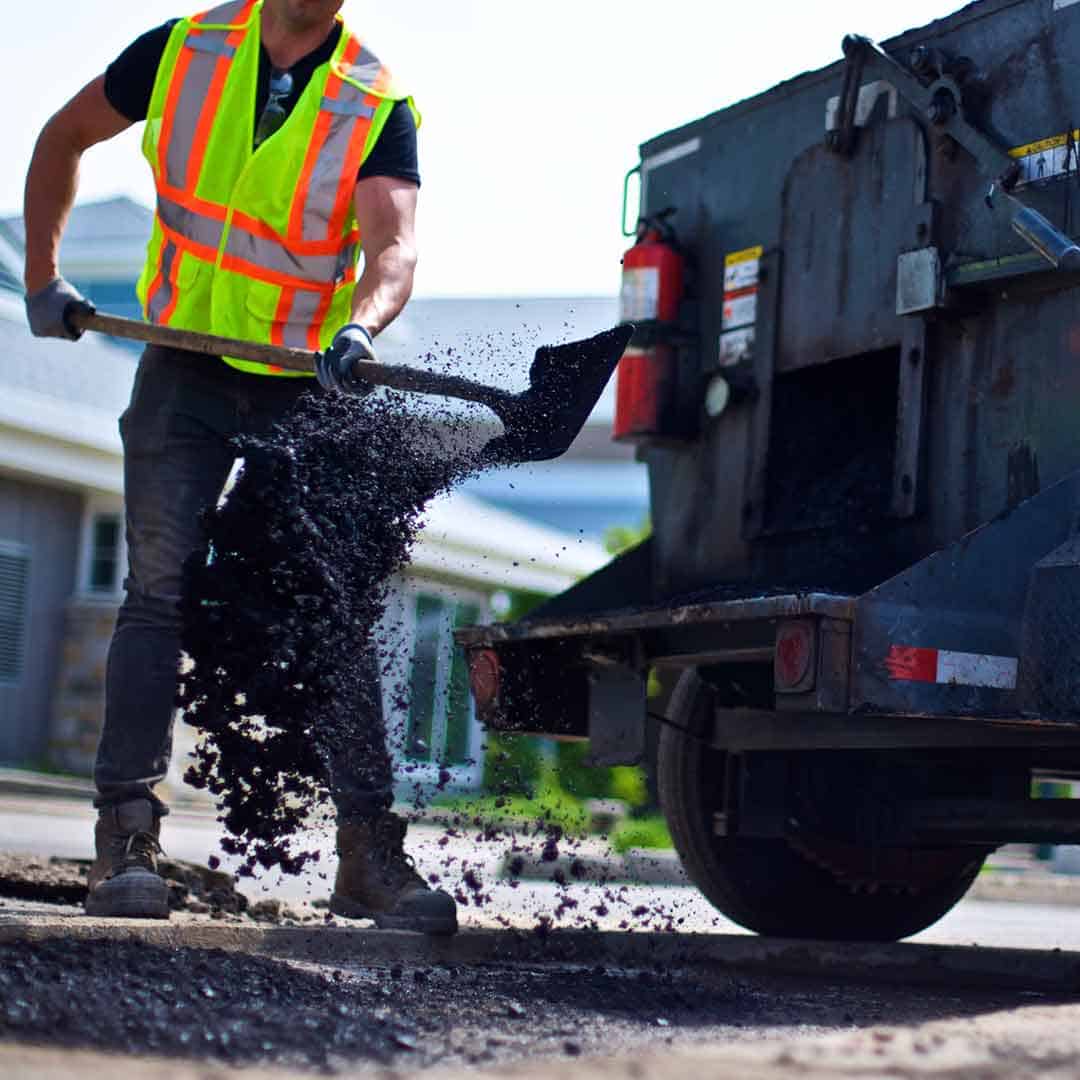 Canadian Property star worker shoveling hot asphalt into a pothole